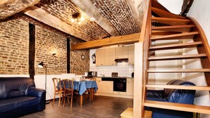 A cozy living area with a sofa, dining table, and a staircase. - Pleasing Holiday Home in Richelle With Garden, Terrace, BBQ (Vise)