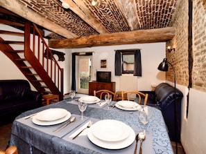 A dining area with a table set for two, a staircase, and a television in the background. - Pleasing Holiday Home in Richelle With Garden, Terrace, BBQ (Vise)