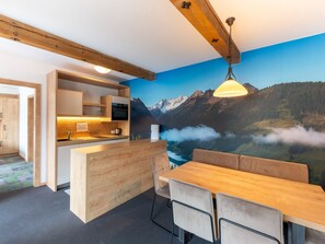 A modern kitchen with wooden cabinets, a built-in oven, and a dining area with a wooden table and chairs. - Apartment in Wald Near Zillertal Arena (Wald im Pinzgau)