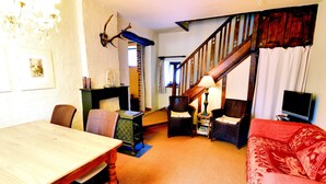 A living room with a wooden staircase, a dining table, a sofa, and a television. - Comfortable Villa, Paliseul (Paliseul)
