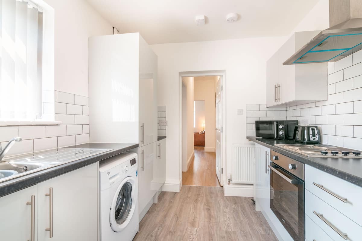 A modern kitchen with a washing machine, microwave, toaster, and oven.