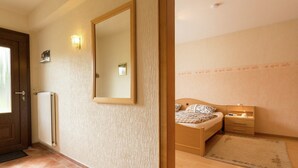 A bedroom with a bed, bedside table, lamp, and a large mirror on the wall. - Ferienwohnung im Sauerland Hillside (Hallenberg)