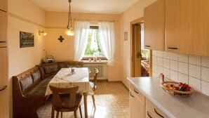 A cozy kitchen with a wooden bench, a dining table, and a fruit basket on the counter. - Ferienwohnung im Sauerland Hillside (Hallenberg)
