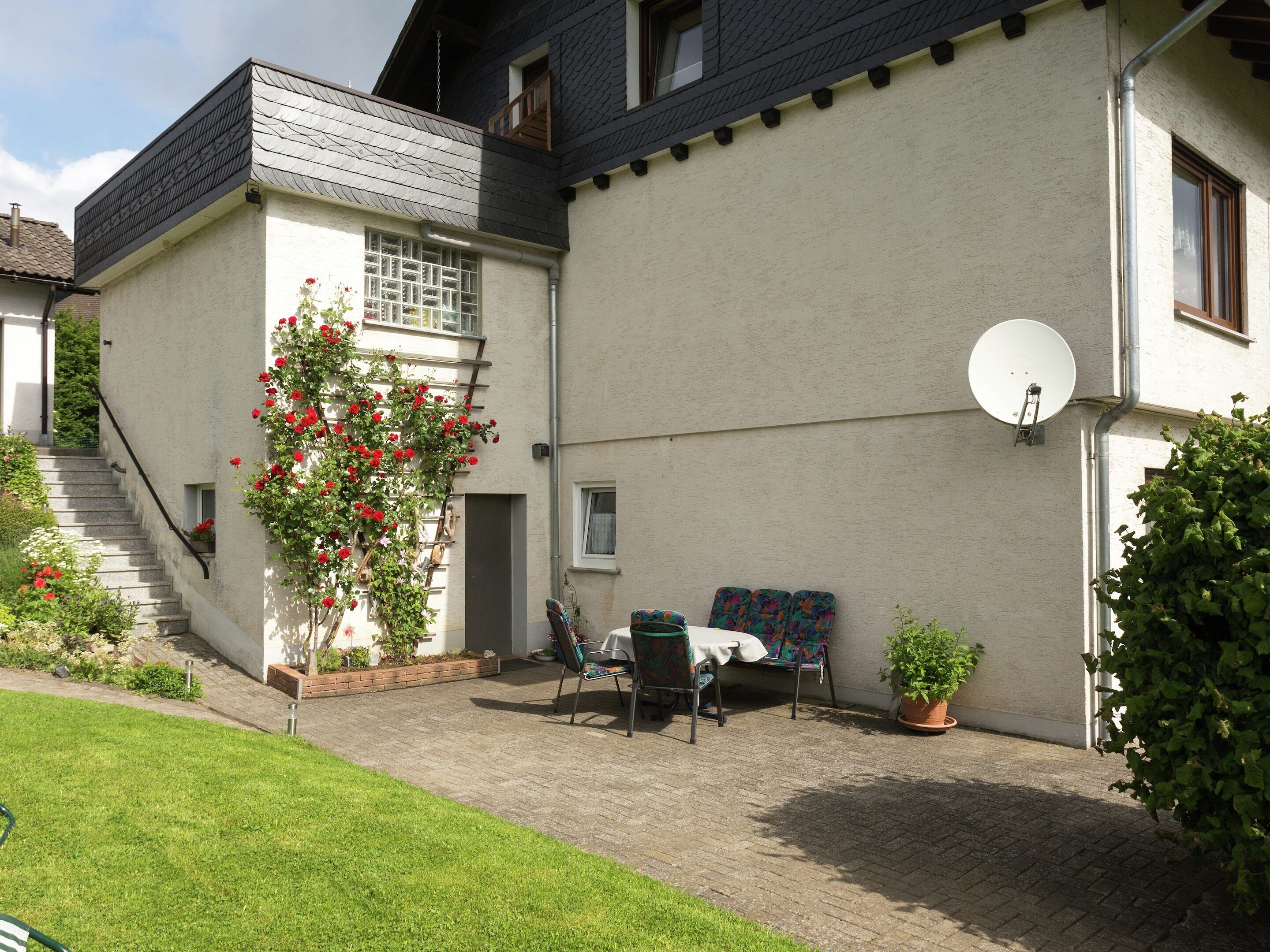 A house with a patio area, a staircase, and a satellite dish.
