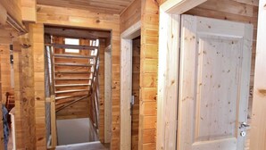 A wooden interior with a staircase leading to an upper level, a white door, and a wooden floor. - Modern Chalet with Hot Tub in Krimml (Krimml)