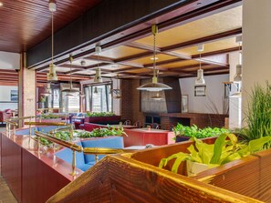 A spacious restaurant with high ceilings, wooden beams, and multiple hanging pendant lights. - Apartment on the Lakeside in Hahnenklee (Goslar)