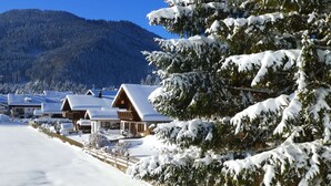 A snow-covered lodge with wooden cabins and a mountain backdrop. - Cozy Alpine Flat in Altenau (Saulgrub)