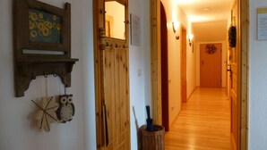 A hallway with wooden doors, a wall-mounted mirror, and a decorative wall hanging. - Cozy Alpine Flat in Altenau (Saulgrub)