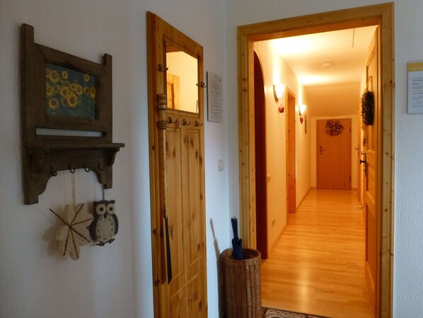 Een gang met houten deuren, een wandspiegel en een decoratieve wandversiering.