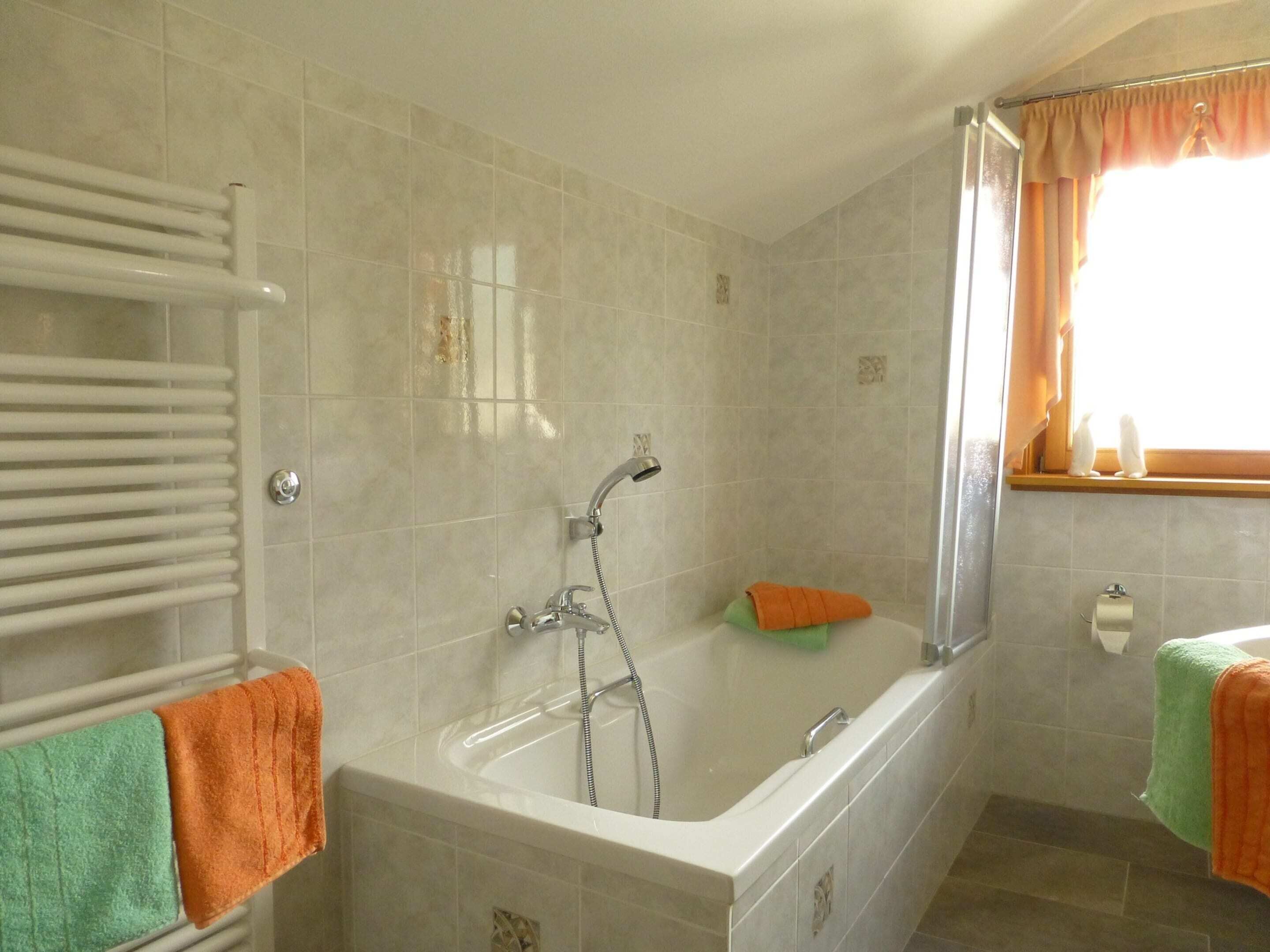 Ein Badezimmer mit einer Badewanne, einer Dusche und einem Fenster mit Vorhängen.