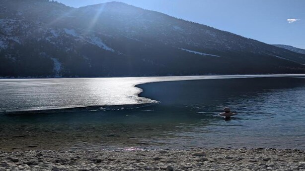 A calm lake with a person in the water, surrounded by mountains and clear skies. - Cozy Alpine Flat in Altenau (Saulgrub)