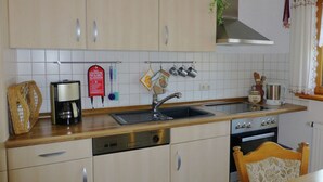 A kitchen with wooden cabinets, a stainless steel sink, a coffee maker, and a stove.