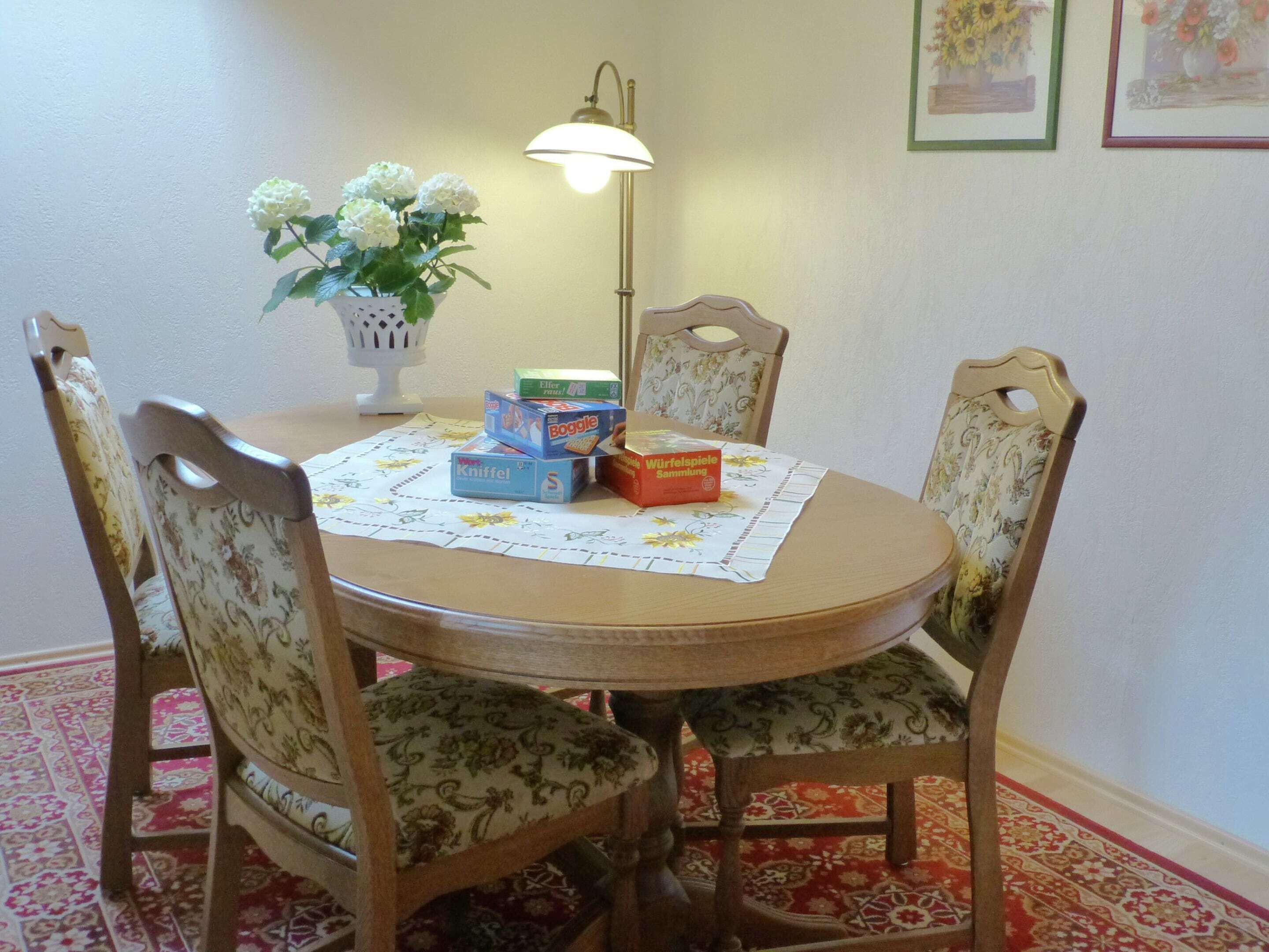 A dining table with floral-patterned chairs, a tablecloth, and various cereal boxes.
