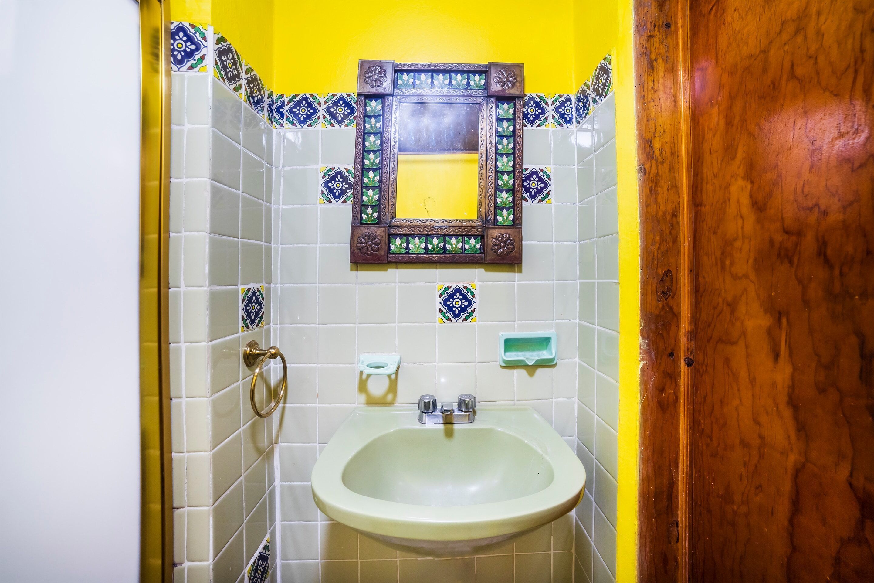 Een badkamer met een wastafel, spiegel en decoratieve tegels.