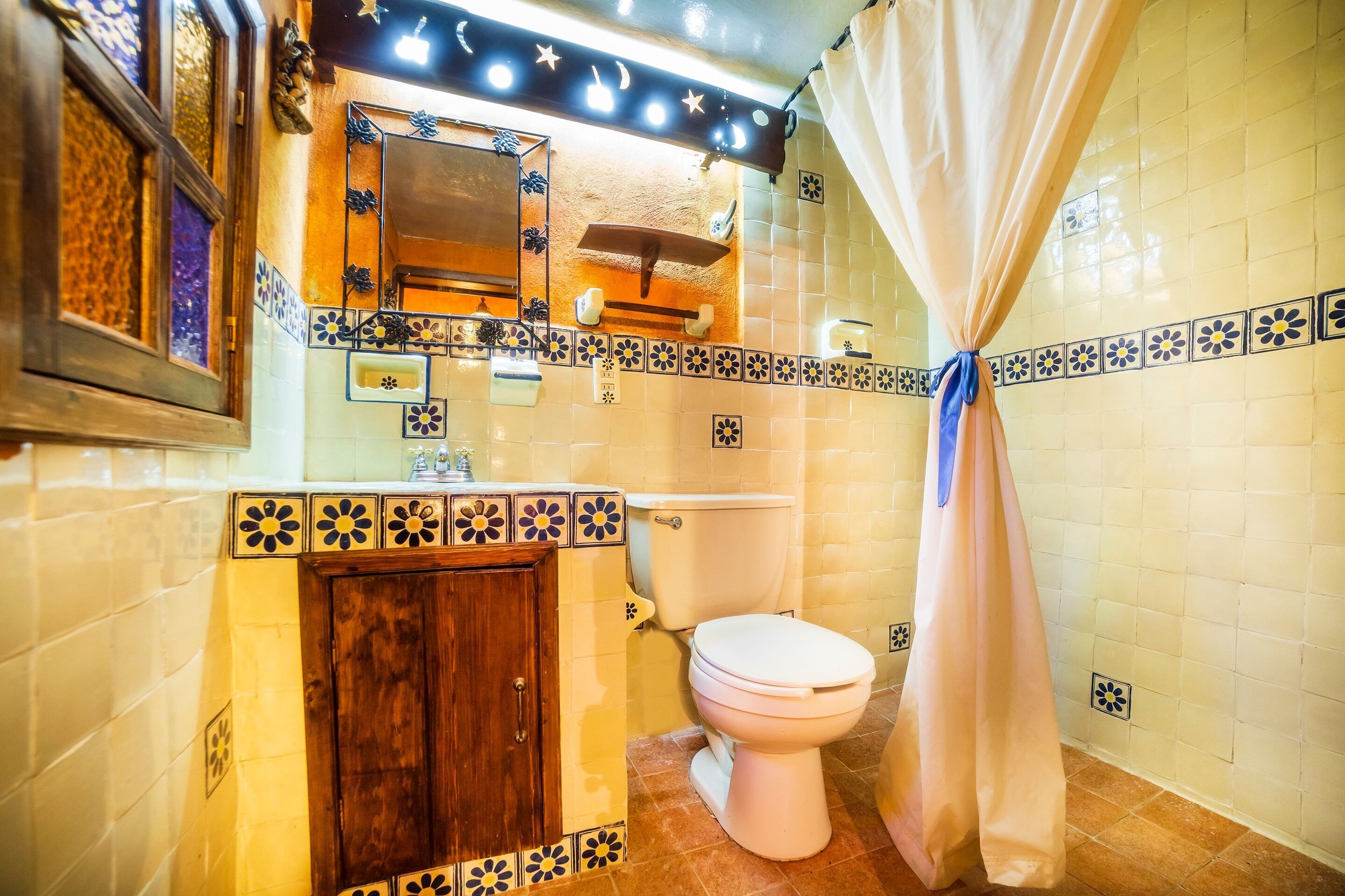 Een badkamer met toilet, wastafel, spiegel en douchegordijn.