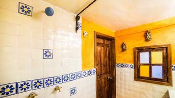 A bathroom with white and blue tiles, a wooden door, and a window with a view.