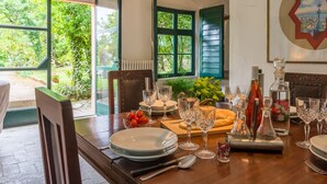 Un coin repas avec une table dressée pour quatre personnes, agrémenté d’une variété de verres et d’un centre de table composé de fleurs fraîches.