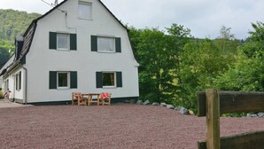 A white two-story house with green shutters, a gravel driveway, and a wooden fence. - Gemutlicher Ruckzugsort in Olsberg-elpe (Olsberg)