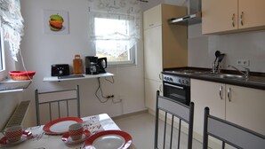 A compact kitchen with a window, a coffee machine, and a dining area with a table set for two. - Gemutlicher Ruckzugsort in Olsberg-elpe (Olsberg)