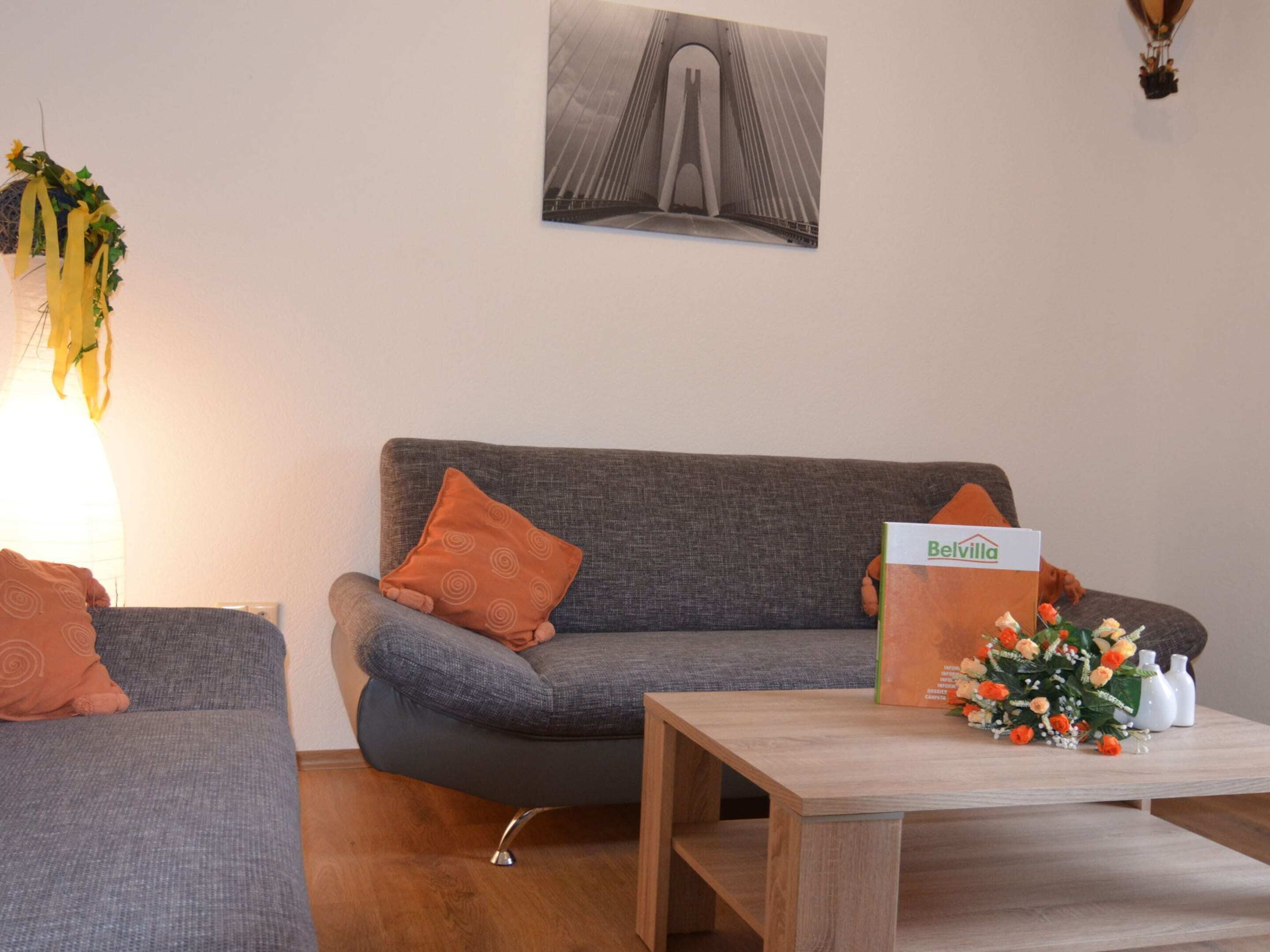 Un salon avec un canapé gris, une table basse en bois et un tableau encadré accroché au mur.