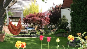 Un jardín con una hamaca, una mesa y sillas, y tulipanes.