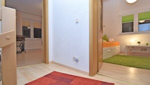 Una sala de estar moderna con piso de madera, un tapete rojo, un sofá, una mesita y una ventana con persianas verdes.