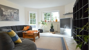 A living room with a sofa, coffee table, TV, and potted plants. - Beautiful Holdiday Home in Ulmen Near the Lake (Ulmen)