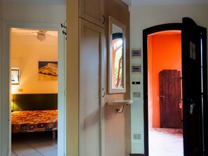 A room with a bed, a window, and a door leading to another room. - Home in Sardinia Near Spiaggia Li Canneddi (Trinità d'Agultu e Vignola)
