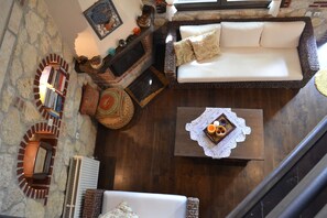 A cozy living room with a fireplace, a sofa, a coffee table, and a bookshelf.