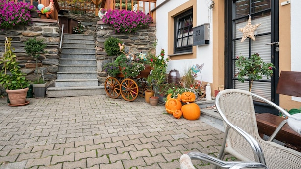 A stone staircase leading to a wooden deck with potted plants and a decorative cart. - Apartment in the Hunsruck Region's Drohn Valley (Merschbach)