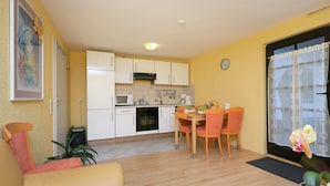A compact kitchen with white cabinets, a microwave, and a dining area with wooden chairs. - Apartment in the Hunsruck Region's Drohn Valley (Merschbach)