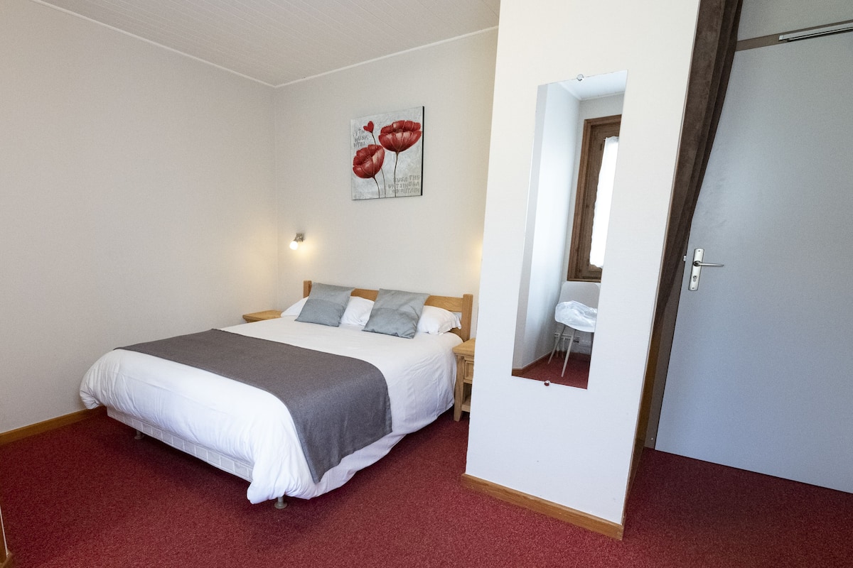 Un dormitorio con cama, mesita de noche, espejo y puerta.