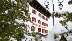 Un hôtel avec des volets rouges et une enseigne indiquant « Hôtel du Centre ».