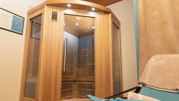 Un sauna avec une structure extérieure en bois, une porte en verre et un porte-serviettes avec des serviettes.