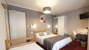Une chambre avec deux lits, un bureau, une chaise, une télévision et un miroir.
