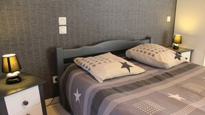 Una cama bien hecha con ropa de cama de diseño estrellado, dos mesitas de noche con lámparas, y una pared con un estampado sutil.