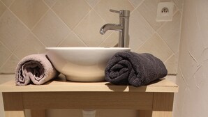 Un tocador de baño con lavamanos, una toalla y un cesto de almacenamiento.
