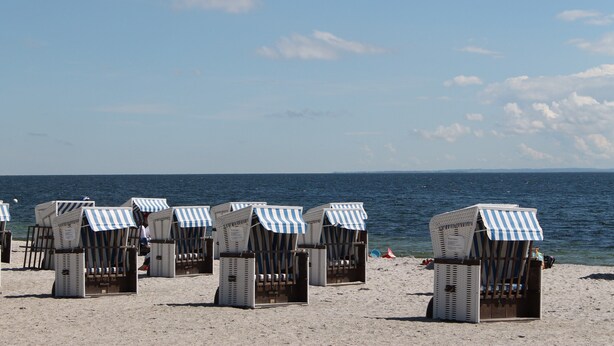 Beach chairs with striped awnings on a sandy beach. - Klutz Garden Apartment (Klütz)