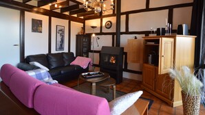 A living room with a black sofa, a pink armchair, a wooden cabinet, and a fireplace. - Amazing Holiday Home in Stavelot With Terrace (Stavelot)