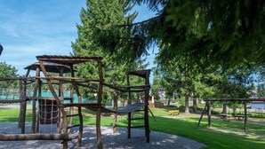 A playground with wooden climbing structures and swings.