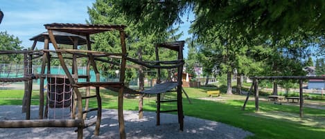 Un parque infantil con estructuras de madera para escalar y columpios.