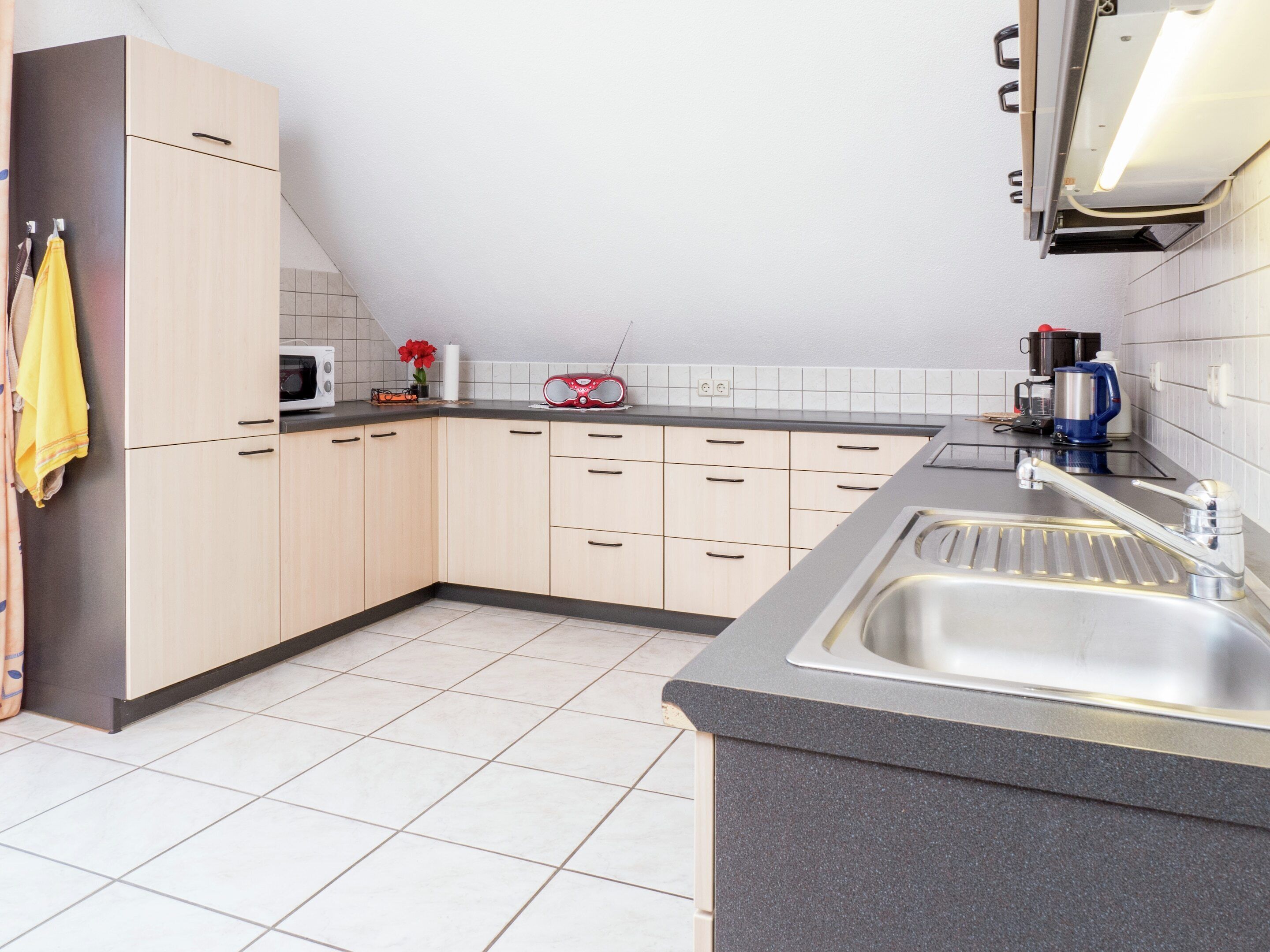 A modern kitchen with a granite countertop, stainless steel sink, and light-colored cabinets.
