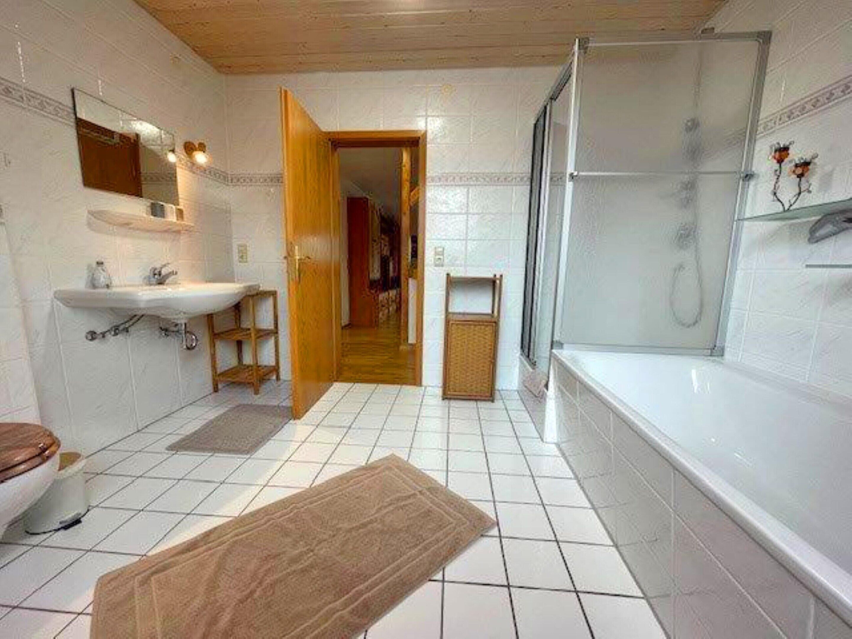 A bathroom with a sink, mirror, toilet, and shower.