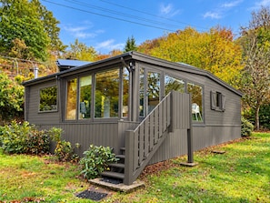 Une petite cabane à un seul étage, dotée d’un porche couvert et d’un escalier menant à l’entrée.