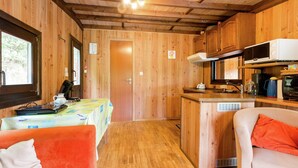 Interno di una baita in legno con angolo cottura, zona pranzo e due sedie.