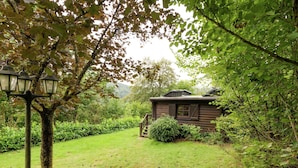 Un rustico chalet con facciata in legno, un sentiero in pietra che vi conduce e un rigoglioso giardino verde.