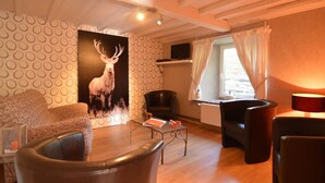 A cozy living room with a large deer painting, comfortable seating, and a television. - Cottage in Ardennes With Heated Pool (La Roche-en-Ardenne)