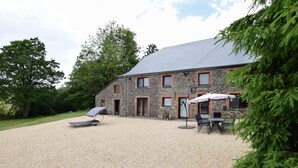 A stone building with a gravel driveway, a lounge chair, and outdoor seating. - Cottage in Ardennes With Heated Pool (La Roche-en-Ardenne)