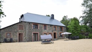 A stone building with a grey roof, outdoor seating, and a gravel driveway. - Cottage in Ardennes With Heated Pool (La Roche-en-Ardenne)