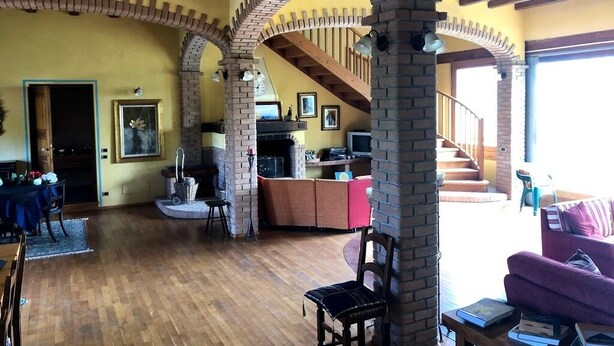 Un'ampia zona giorno con archi in mattoni a vista, una scala in legno e un camino.